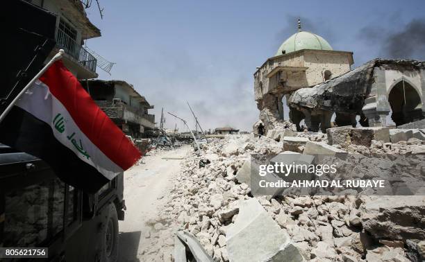 An Iraqi flag waves as it hangs outside a Counter-Terrorism Service humvee driving past the destroyed Al-Nuri Mosque in the Old City of Mosul on July...