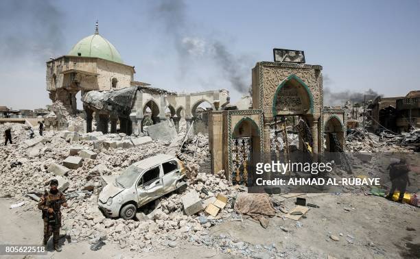 Members of the Iraqi Counter-Terrorism Service gather outside the destroyed gate of the Al-Nuri Mosque while others inspect the interiors, in the Old...