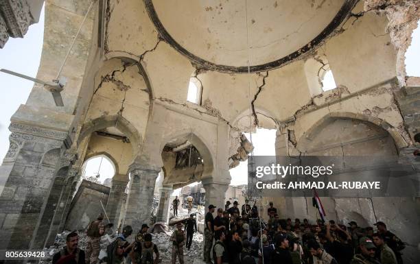 Members of the Iraqi forces along with high-ranking officers gather to take pictures in the remains of the Grand Mosque of Al-Nuri at the site where...