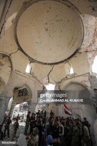 Members of the Iraqi forces along with high-ranking officers gather to take pictures in the remains of the Grand Mosque of Al-Nuri at the site where...