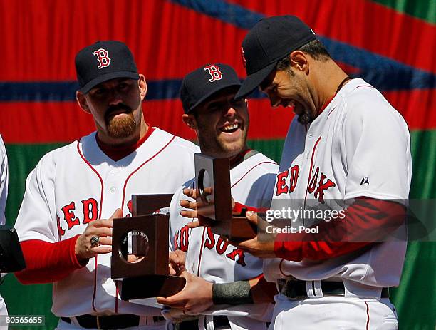 Kevin Youkilis, Dustin Pedroia and Mike Lowell of the Boston Red Sox look at their 2007 World Series rings during pre-game ceremonies before the Red...