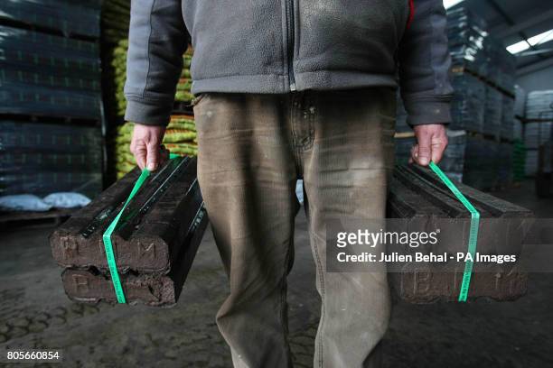 Man carries two bales of Peat Briquettes in Ahern Fuels in Urlingford, Co.Kilkenny, on Budget day when the Government has signalled it will introduce...