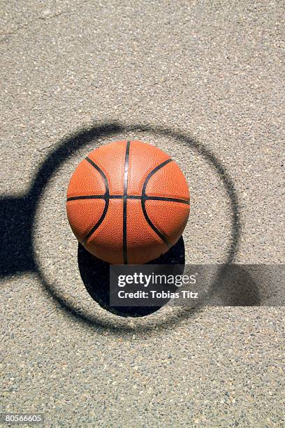 a basketball in the middle of a shadow hoop - basketball hoop stockfoto's en -beelden