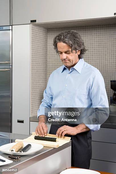 a mature man preparing sushi in the kitchen - making sushi stock pictures, royalty-free photos & images