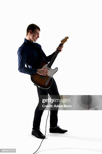 studio shot of a man playing an electric guitar - plucking an instrument foto e immagini stock