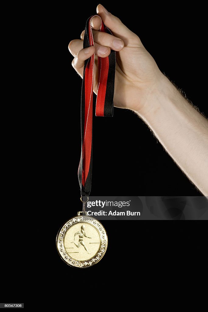 A hand holding a gold medal