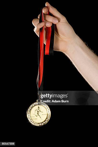 a hand holding a gold medal - médaillé photos et images de collection