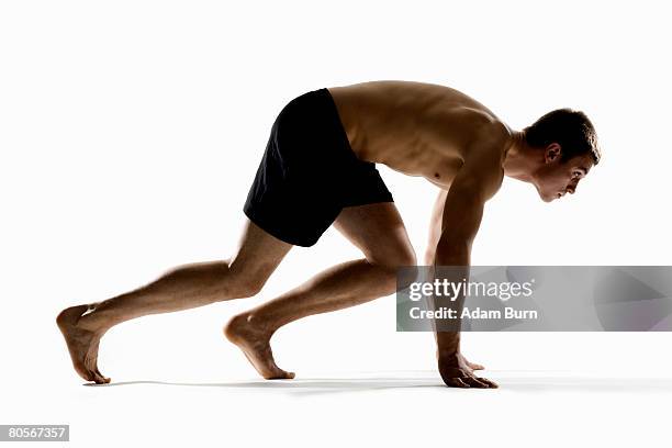 studio shot of a male runner preparing to race - barefoot men - fotografias e filmes do acervo