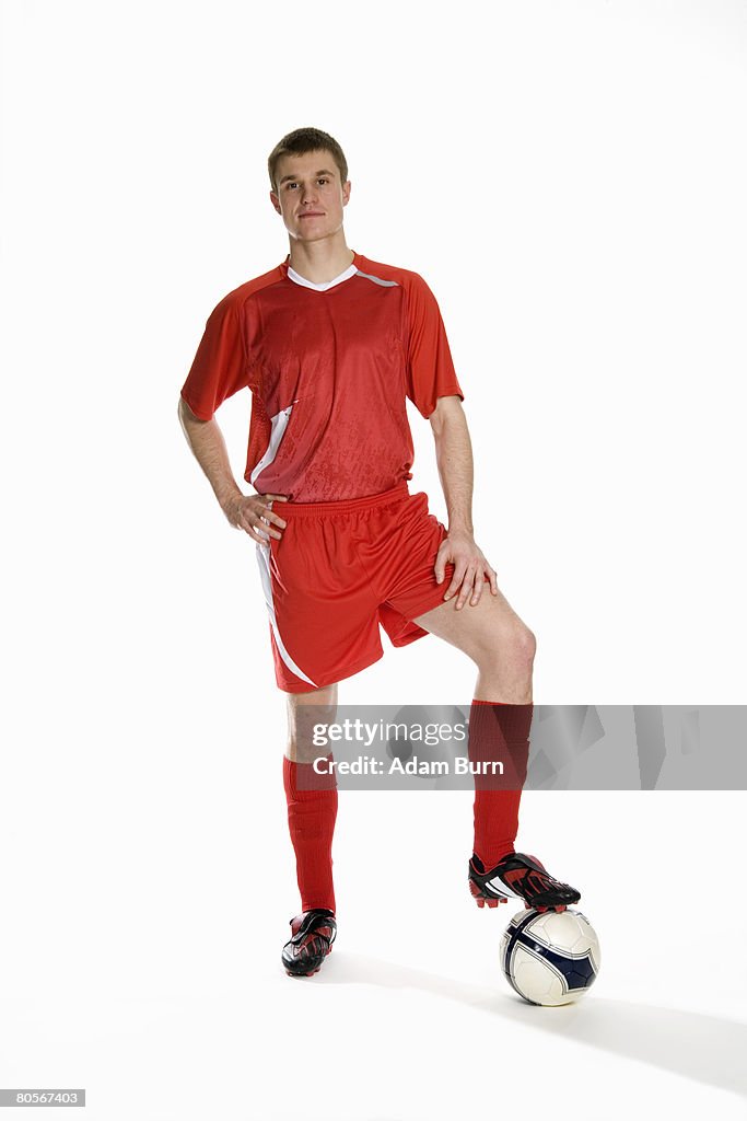 Studio portrait of soccer player with his foot on a soccer ball