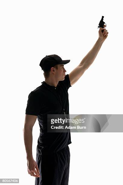 studio shot of referee holding a starting gun - pistola de salida fotografías e imágenes de stock