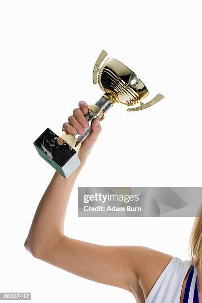 a female athlete's arm holding up a winning trophy - first light awards inside stock-fotos und bilder