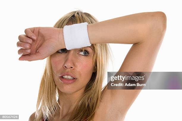 a portrait of a woman sweating and wiping her brow - zweetband stockfoto's en -beelden