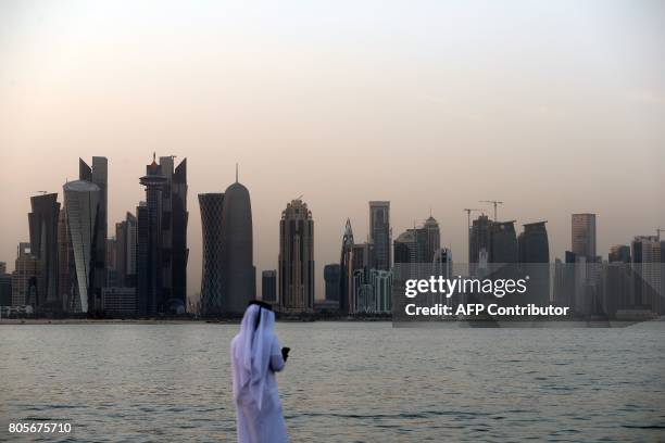 Man looks at his phone on the corniche in the Qatari capital Doha on July 2, 2017. / AFP PHOTO / STR