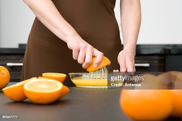 a woman juicing oranges - squeezing imagens e fotografias de stock
