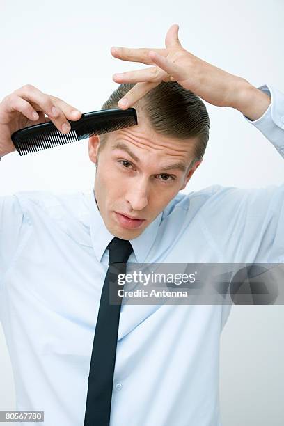 a mid adult man combing his hair - slick hair stock-fotos und bilder