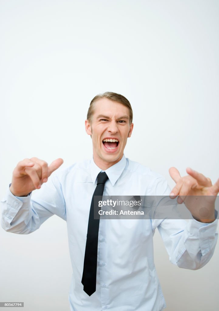 A mid adult man raising his arms in a confrontational gesture