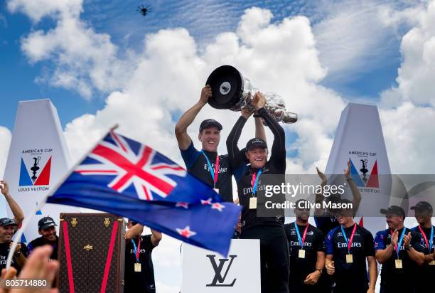 Peter Burling, Helmsman and Glenn Ashby, skipper of Emirates Team New Zealand lift the America's Cup trophy as Emirates Team New Zealand win race 9...