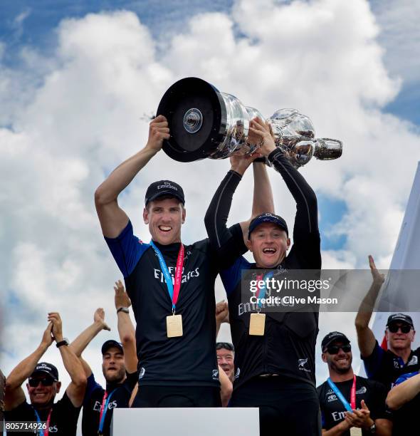 Peter Burling, Helmsman and Glenn Ashby, skipper of Emirates Team New Zealand lift the America's Cup trophy as Emirates Team New Zealand win race 9...