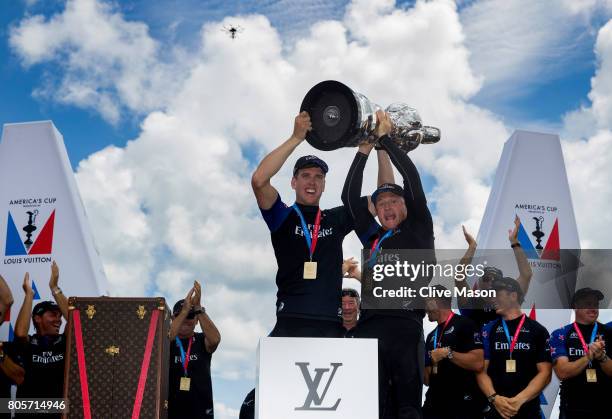 Peter Burling, Helmsman and Glenn Ashby, skipper of Emirates Team New Zealand lift the America's Cup trophy as Emirates Team New Zealand win race 9...