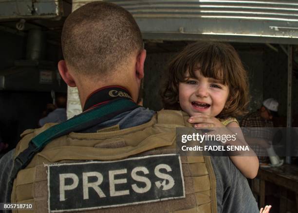 Press photographer helps carry a child who fled from the Old City of Mosul, in the city's western industrial district on July 2 during the government...