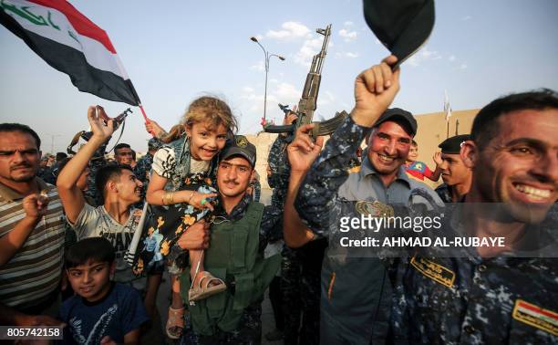 Members of the Iraqi federal police pose for a picture with children during a celebration in the Old City of Mosul, where the gruelling battle to...