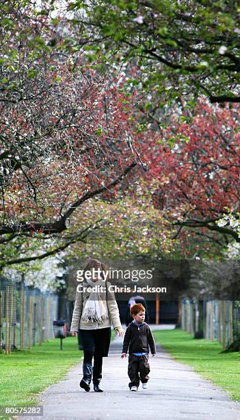 Young boy and a woman walk in Battersea Park on April 9, 2008 in London, England. After a spell of cold weather and snow over the weekend the sun is...