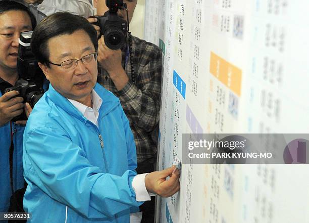 South Korea's conservative Grand National Party Chairman Kang Jae-Sup plasters victory marks on candidates who won in the parliamentary election at...