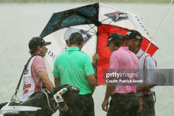 Kyle Stanley of the United States and Charles Howell III of the United States take cover during a rainstorm during the final round of the Quicken...