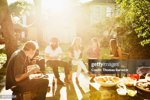 friends in discussion while eating dinner in backyard on sunny summer evening - texas house stock pictures, royalty-free photos & images