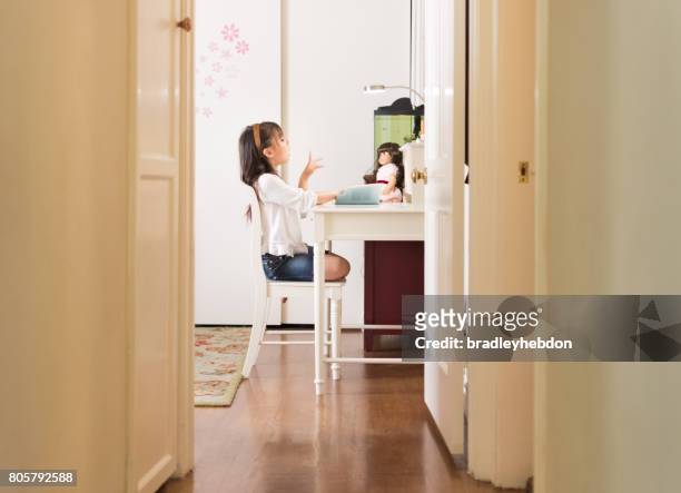 pretty eurasian girl reads book to doll in bedroom - american girl doll stock pictures, royalty-free photos & images