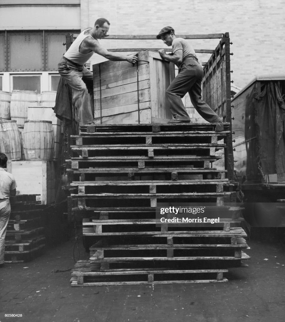 Loading Crate Docks Loading dock workers lift a large wooden crate from the bed of a ...