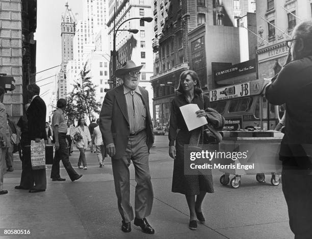 American photographer Ansel Adams walks along 5th Avenue with an unidentified woman, New York, New York, late 1970s.