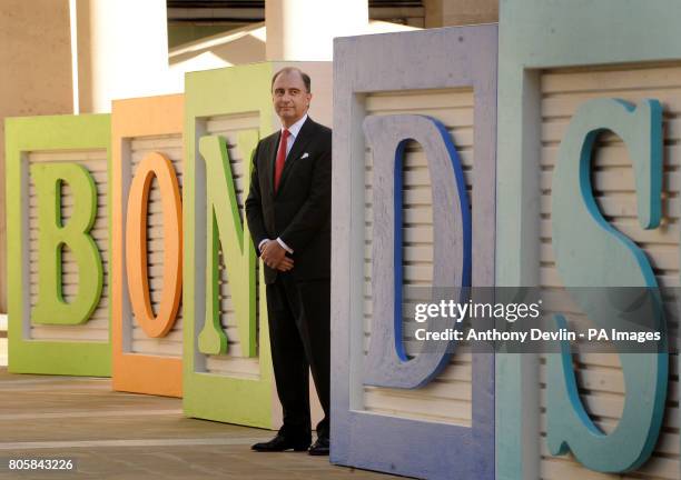 Chief Executive of the LSE, Xavier Rolet, poses bedside signage outside the London Stock Exchange, to promote a new electronic retail bond service.