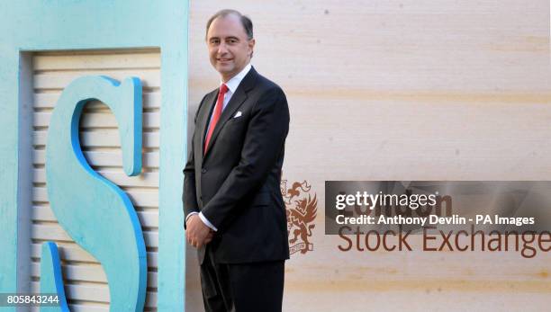 Chief Executive of the LSE, Xavier Rolet, poses bedside signage outside the London Stock Exchange, to promote a new electronic retail bond service.