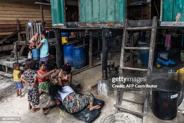 This picture taken on May 14, 2017 shows female members of the Moken tribe taking care of children in front of one of their homes in Makyone Galet...