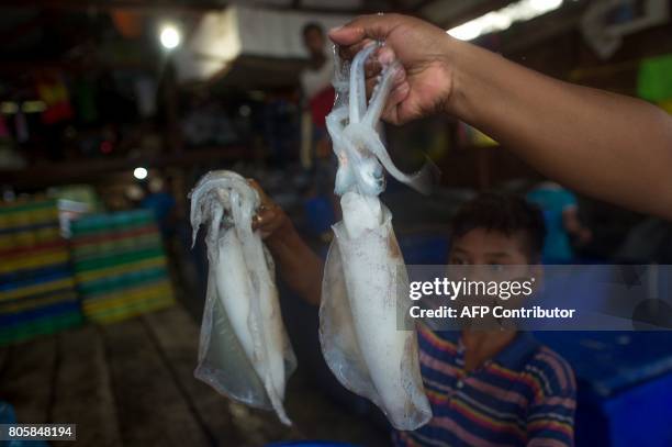 This picture taken on May 14, 2017 shows Moken fishermen holding cuttlefish for sale at a fishing market in Nyaung Wee village in the Myeik...