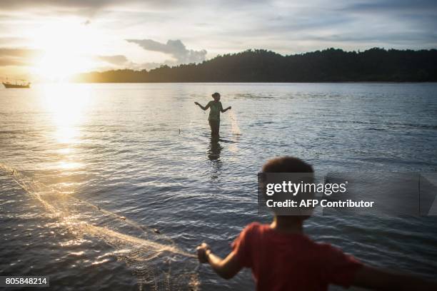 This picture taken on May 13, 2017 shows a Moken woman and boy retrieving a net in shallow waters in Makyone Galet village in the Myeik Archipelago,...