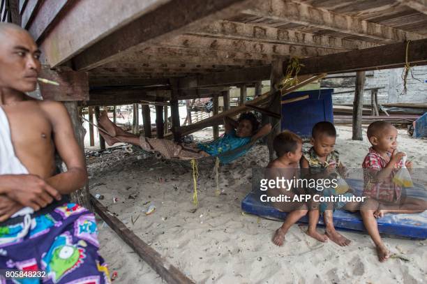 This picture taken on May 13, 2017 shows a Moken family sitting underneath one of their stilt homes in Makyone Galet village in the Myeik...