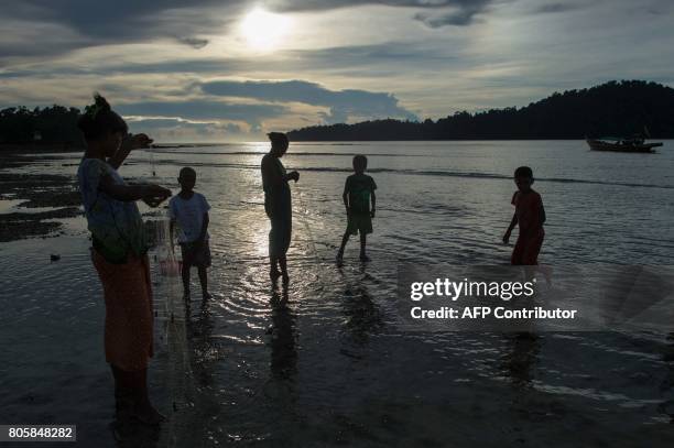 This picture taken on May 13, 2017 shows Moken women and children retrieving a net in shallow waters in Makyone Galet village in the Myeik...