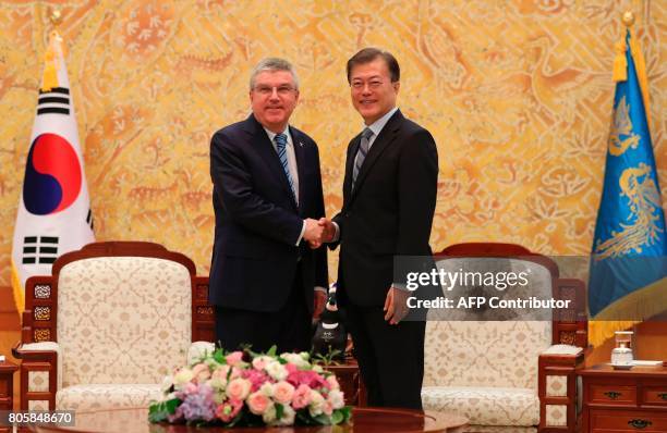 South Korean President Moon Jae-in shakes hands with International Olympic Committee President Thomas Bach before a meeting at the presidential Blue...