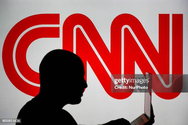 Man is seen holding with a smart device in front of a CNN logo in this photo illustration on 2 July, 2017.