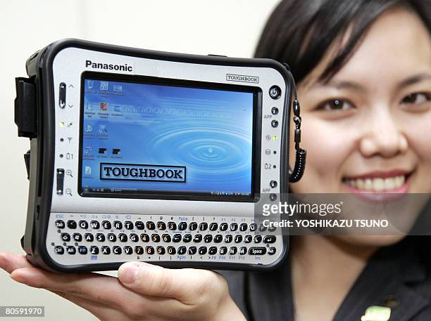 An employee for Japanese electronics giant Matsushita Electric Industrial displays the prototype model of the heavy-duty handheld PC "Toughbook",...