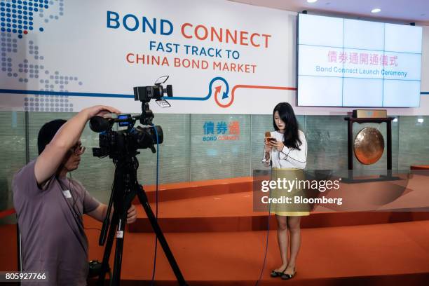 News reporter prepares to speak to a television camera in front of signage for the China-Hong Kong Bond Connect at the Hong Kong Stock Exchange in...
