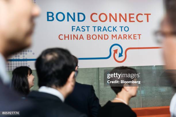 Attendees walk past signage for the China-Hong Kong Bond Connect at the Hong Kong Stock Exchange in Hong Kong, China on Monday, July 3, 2017. The...