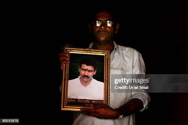 Vijay Bakamuar, father of Pravin Bakamuar who committed suicide last winter, holds his son's portrait in the family home on April 2008 in the village...