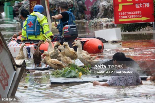 This picture taken on July 2, 2017 shows rescue workers helping people on a flooded street in Loudi, Hunan province. Days of torrential rain in Hunan...