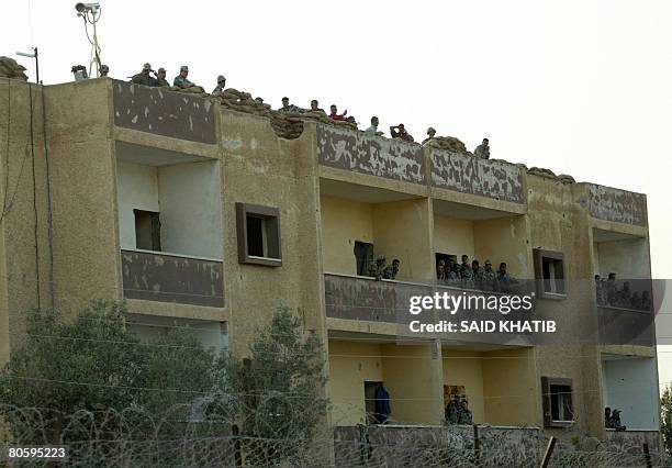 Pictured through the border fence from the Palestinian territories, Egyptian soldiers stand guard on the roof of an abandoned building on the...