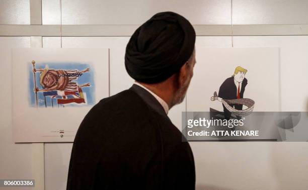 Iranian reformist cleric Mahmoud Doaei looks at cartoons of US President Donald J. Trump at an exhibition of the Islamic Republic's 2017...