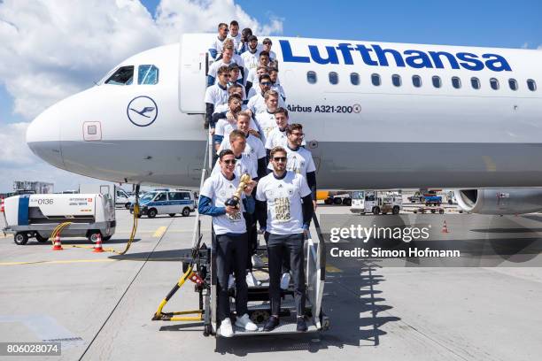 Julian Draxler and his team mates present the trophy as they depart the plane carrying the Germany National Football Team during the arrival at...