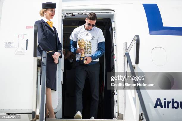 Julian Draxler presents the trophy as he departs the plane carrying the Germany National Football Team during the arrival at Frankfurt International...